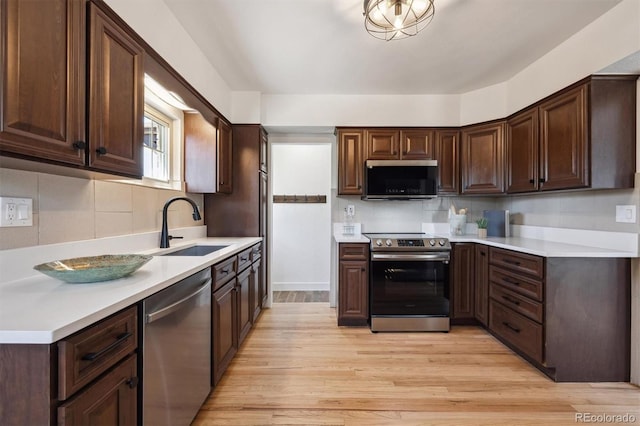 4434 Grove St, Denver, CO 80211 - kitchen featuring stainless steel appliances, a sink, dark brown cabinets, light wood-style flooring, and light countertops