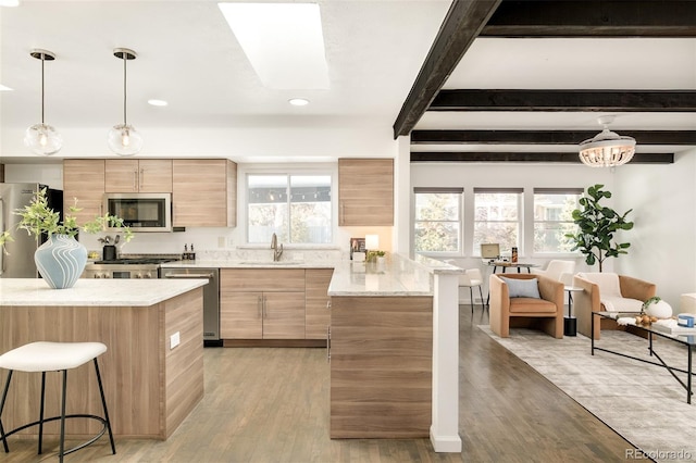 kitchen featuring light stone counters, decorative light fixtures, a sink, stainless steel appliances, and beam ceiling