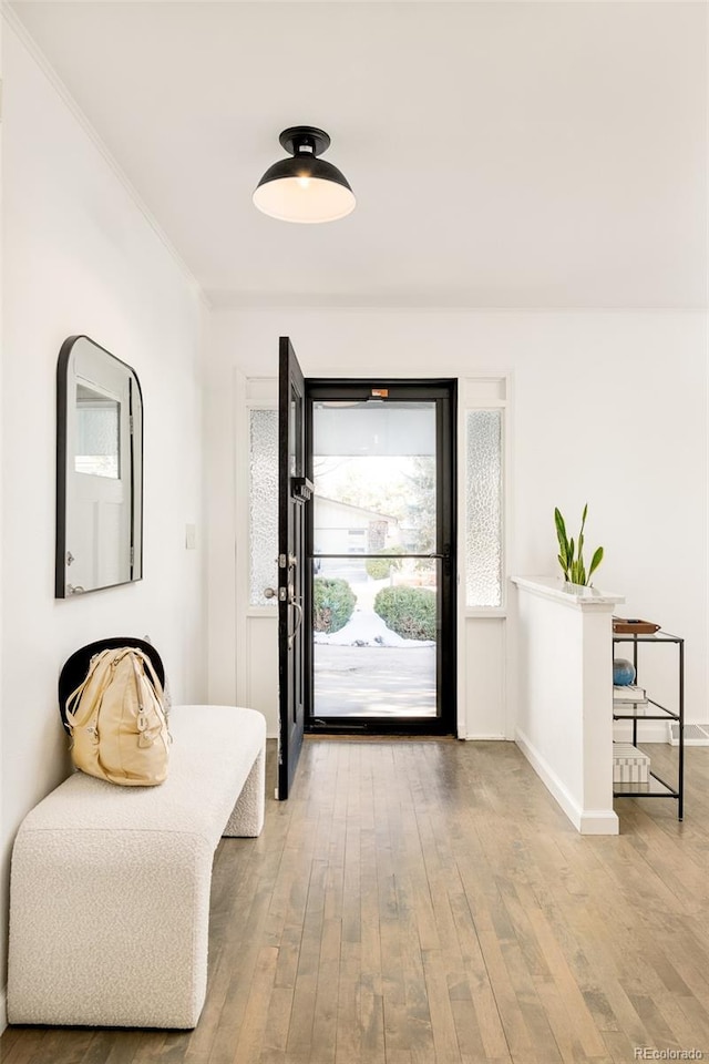 entrance foyer featuring baseboards, light wood-type flooring, and crown molding