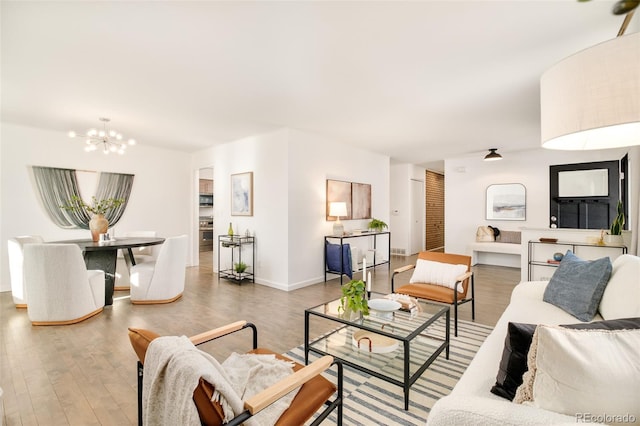 living room with baseboards, wood finished floors, and an inviting chandelier