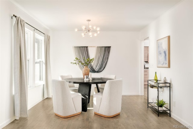 dining space featuring baseboards, a chandelier, and wood finished floors