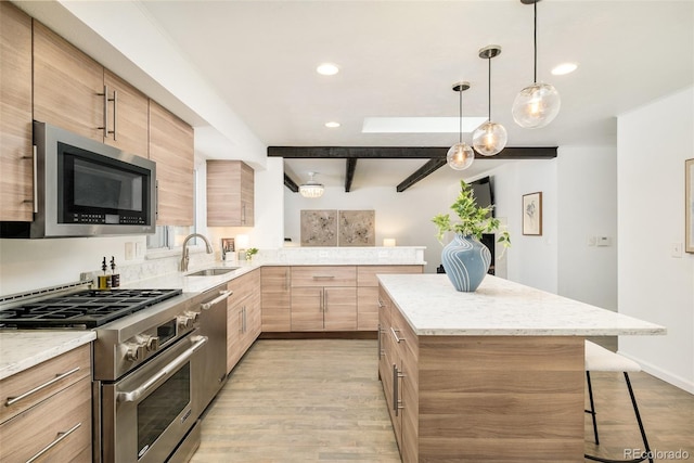 kitchen with stainless steel appliances, a sink, a kitchen breakfast bar, light wood-type flooring, and pendant lighting