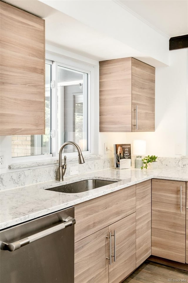 kitchen featuring light stone counters, dark wood-style flooring, light brown cabinetry, a sink, and dishwasher