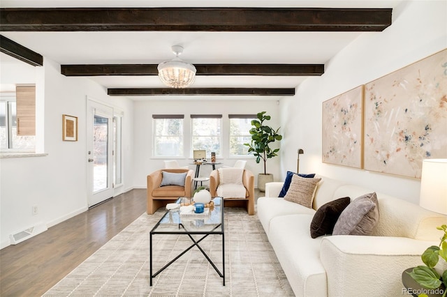 living room featuring light wood-type flooring, baseboards, visible vents, and beam ceiling