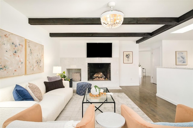 living area featuring wood finished floors, a fireplace with flush hearth, beam ceiling, and baseboards