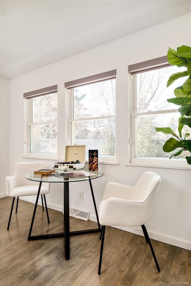 office space with plenty of natural light, visible vents, baseboards, and wood finished floors