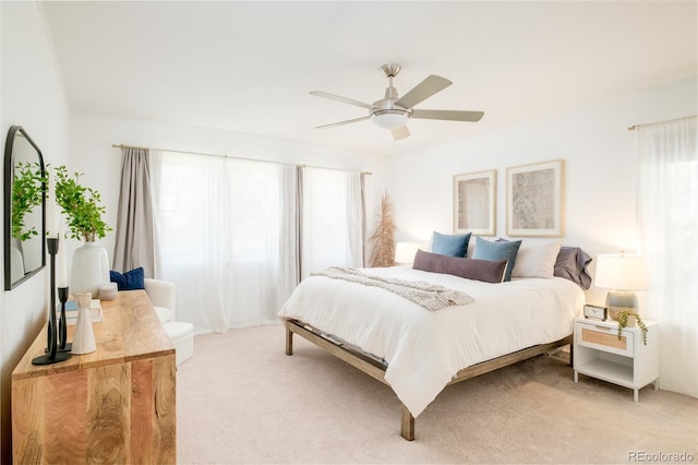 bedroom with a ceiling fan, light colored carpet, and multiple windows