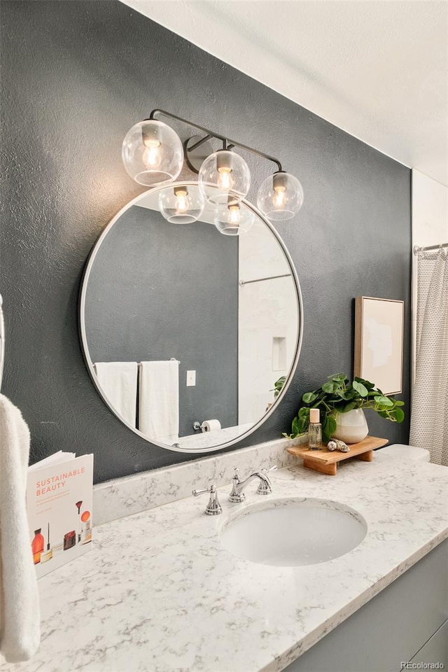 bathroom with a textured wall and vanity