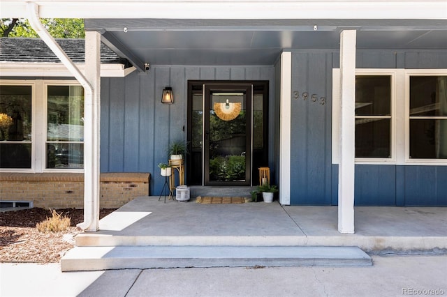 view of exterior entry with covered porch and board and batten siding