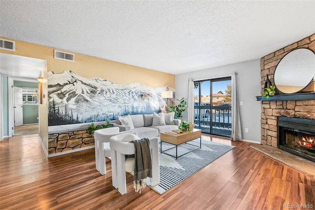 8600 E Alameda Ave Unit 13-108, Denver, CO 80247 - living area featuring a textured ceiling, wood finished floors, and a stone fireplace
