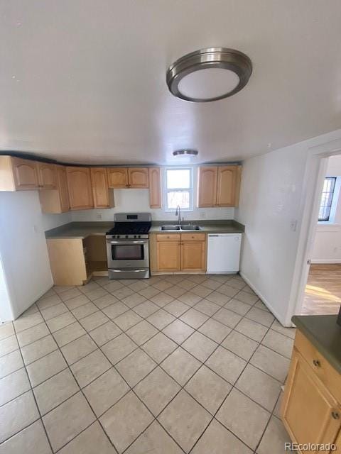 kitchen with light tile patterned floors, stainless steel range with gas stovetop, sink, and white dishwasher