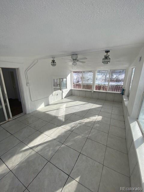 unfurnished living room featuring ceiling fan and light tile patterned floors