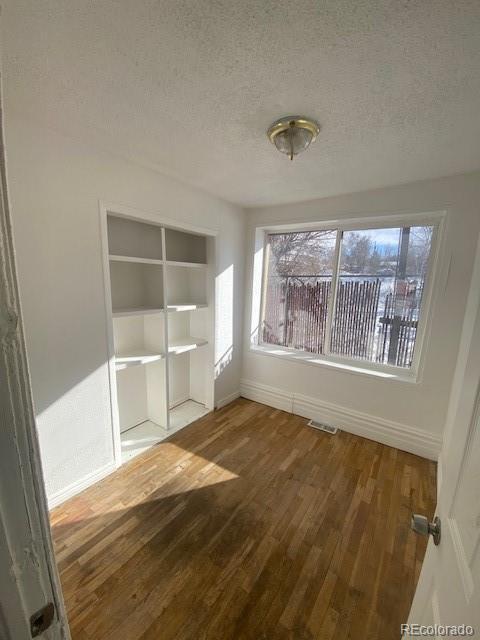 unfurnished bedroom featuring hardwood / wood-style flooring, a closet, and a textured ceiling