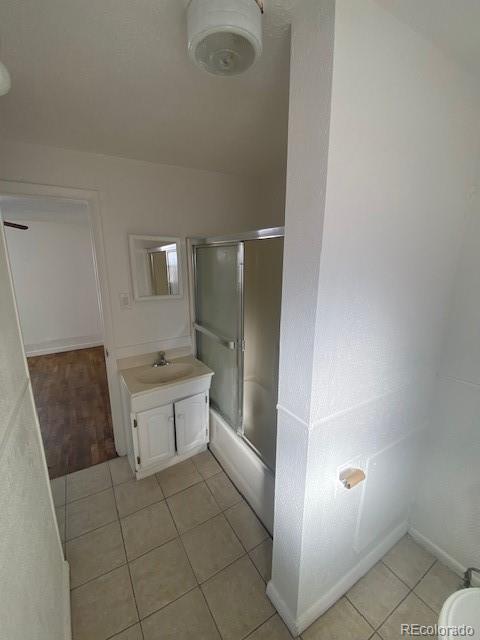 bathroom with enclosed tub / shower combo, tile patterned floors, and vanity