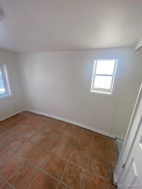 empty room featuring dark tile patterned floors and a textured ceiling