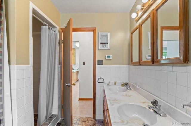 561 Quartz Cir, Bailey, CO 80421 - bathroom featuring double vanity, tiled shower, tile walls, and a wainscoted wall