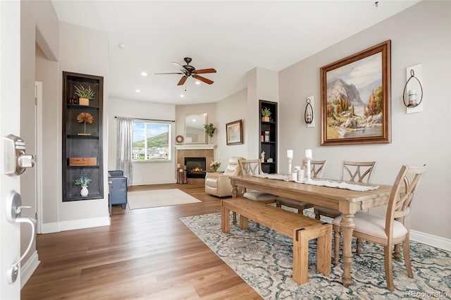 737 Novick Ct, Castle Rock, CO 80109 - dining area with wood finished floors, a tiled fireplace, ceiling fan, baseboards, and recessed lighting