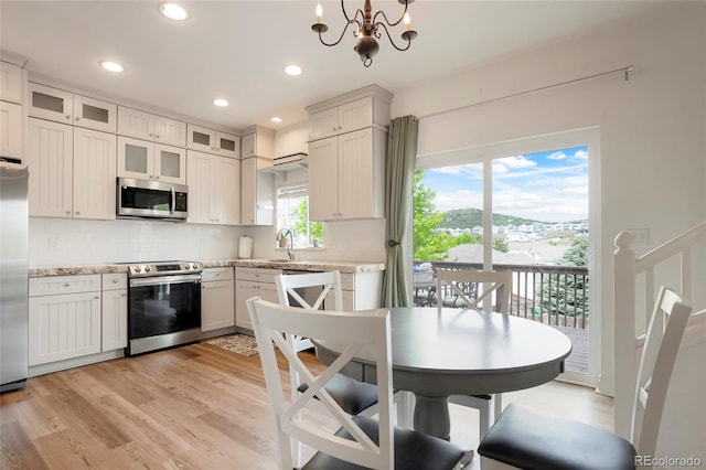 737 Novick Ct, Castle Rock, CO 80109 - kitchen featuring appliances with stainless steel finishes, a chandelier, tasteful backsplash, light wood finished floors, and a sink