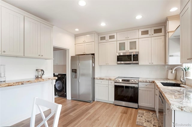 737 Novick Ct, Castle Rock, CO 80109 - kitchen with appliances with stainless steel finishes, washer / dryer, a sink, light wood-style floors, and light stone counters