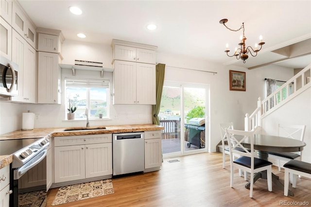 737 Novick Ct, Castle Rock, CO 80109 - kitchen with stainless steel appliances, a sink, light wood finished floors, a chandelier, and recessed lighting