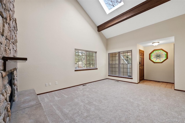 unfurnished living room featuring a skylight, high vaulted ceiling, beamed ceiling, light colored carpet, and a fireplace