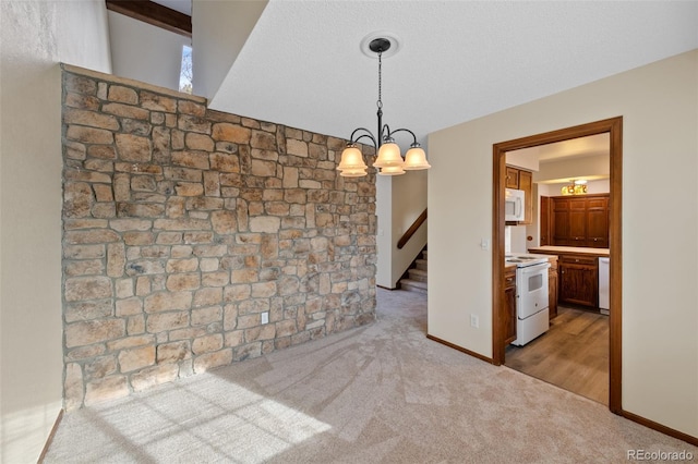 unfurnished dining area featuring an inviting chandelier, light colored carpet, and a textured ceiling