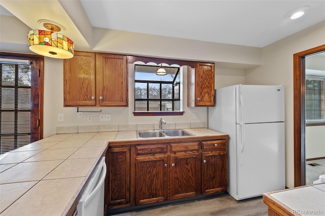 kitchen with plenty of natural light, sink, tile counters, and white appliances