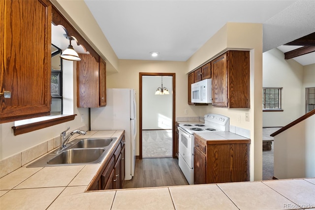 kitchen featuring sink, tile counters, white appliances, and decorative light fixtures