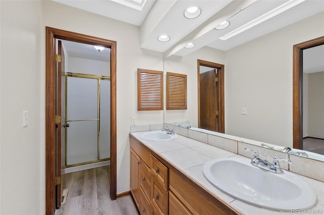 bathroom with hardwood / wood-style flooring, vanity, a skylight, and a shower with shower door