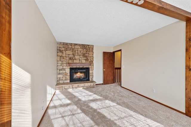 unfurnished living room with a stone fireplace, carpet floors, and a textured ceiling