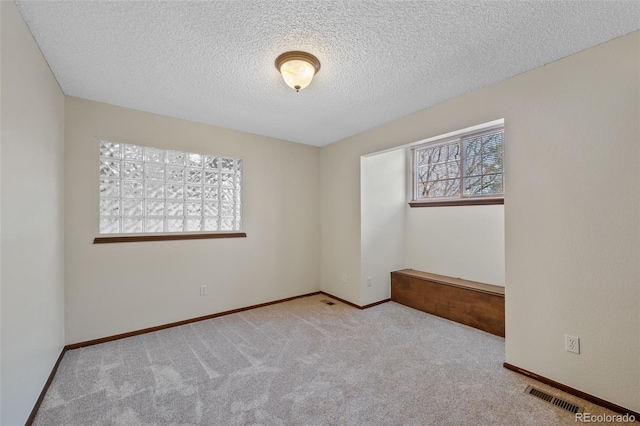 carpeted empty room featuring a textured ceiling