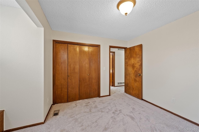 unfurnished bedroom featuring light carpet, a closet, and a textured ceiling