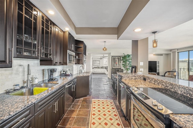 kitchen with dark brown cabinetry, sink, light stone counters, hanging light fixtures, and appliances with stainless steel finishes