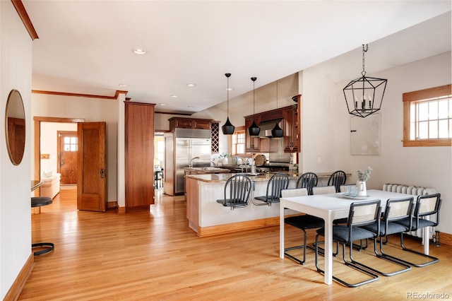 dining area with an inviting chandelier, ornamental molding, light hardwood / wood-style flooring, and a wealth of natural light