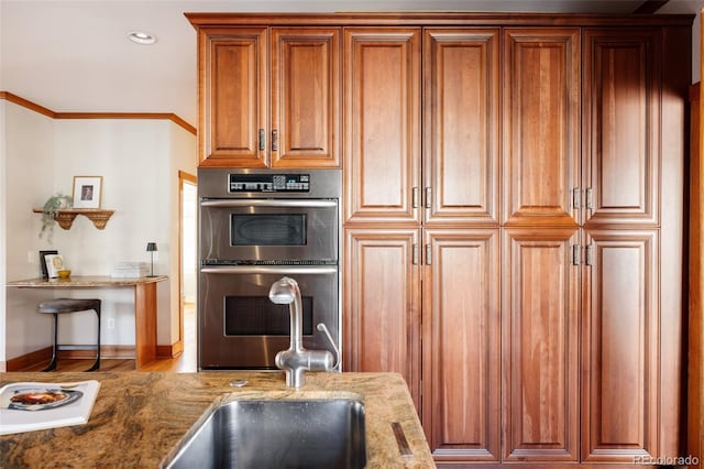 kitchen with hardwood / wood-style floors, sink, crown molding, light stone countertops, and stainless steel double oven