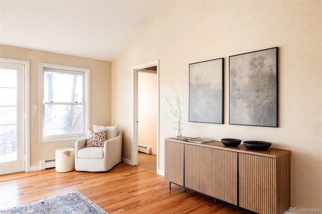 living area with lofted ceiling, light hardwood / wood-style flooring, and a baseboard heating unit