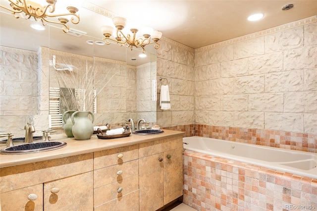 bathroom featuring vanity, tile walls, a notable chandelier, and tiled bath