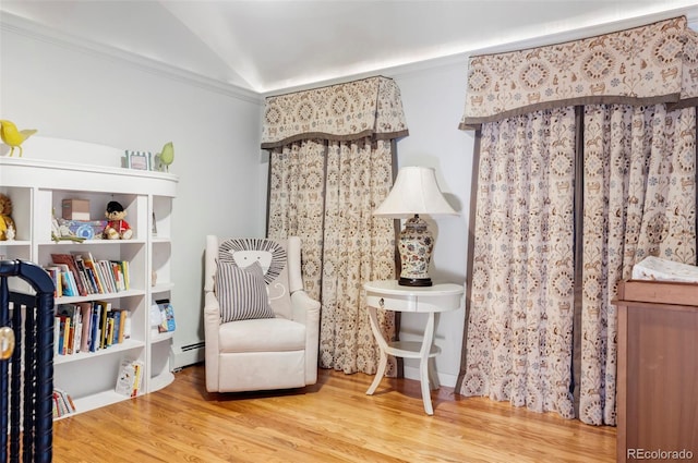 sitting room with baseboard heating, ornamental molding, wood-type flooring, and vaulted ceiling