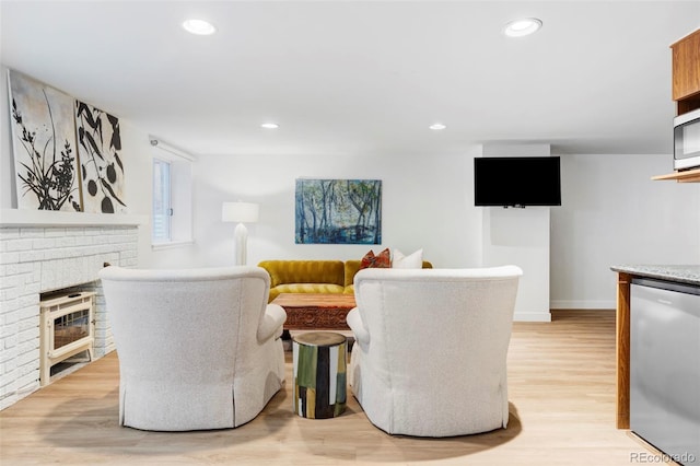 living room featuring a brick fireplace and light hardwood / wood-style flooring