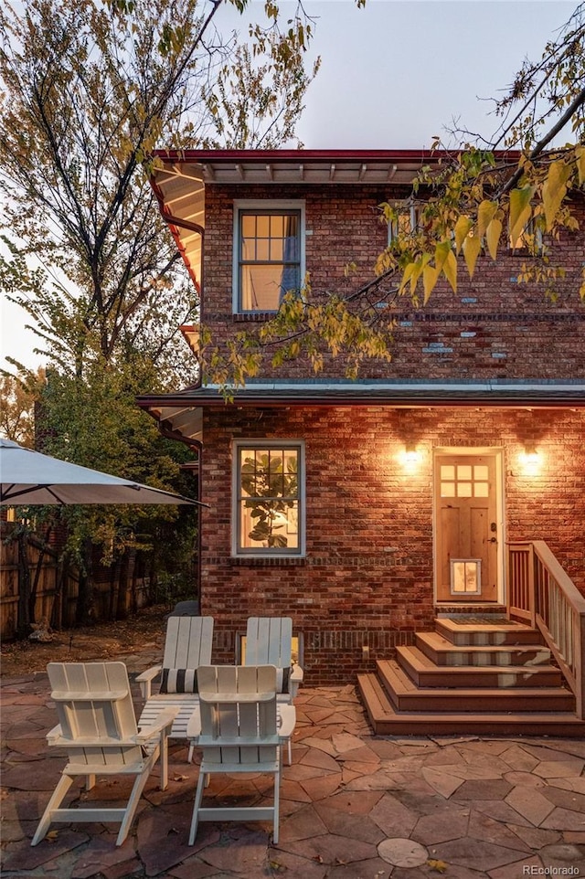 back house at dusk featuring a patio