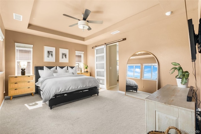 4778 Ravencrest Pl, Castle Rock, CO 80108 - bedroom with a barn door, a tray ceiling, light carpet, and ceiling fan