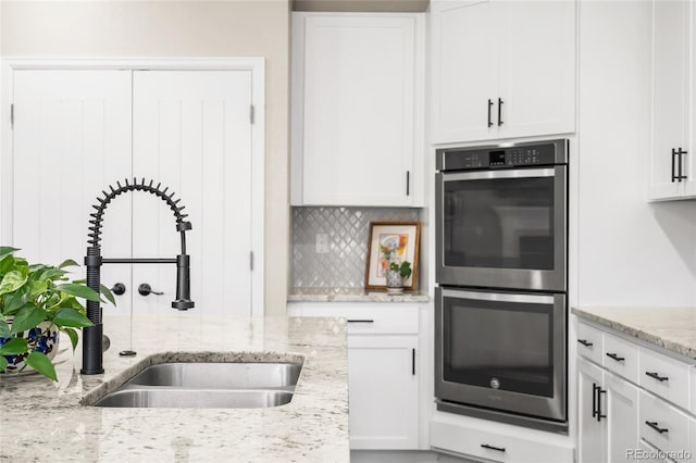4778 Ravencrest Pl, Castle Rock, CO 80108 - kitchen with double oven, white cabinetry, light stone counters, and tasteful backsplash