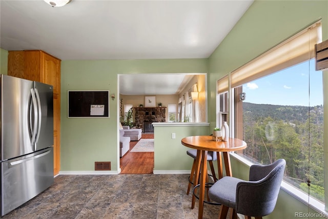 8701 Majestic View Dr, Conifer, CO 80433 - kitchen with freestanding refrigerator, baseboards, a stone fireplace, stone finish flooring, and brown cabinetry