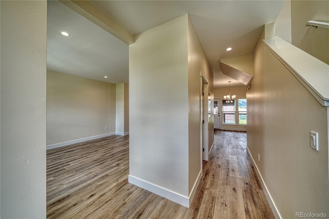 corridor with light hardwood / wood-style flooring and an inviting chandelier