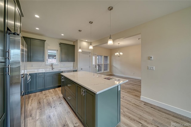 kitchen featuring sink, light stone counters, light hardwood / wood-style flooring, pendant lighting, and a kitchen island