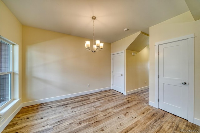 unfurnished room with a chandelier and light wood-type flooring