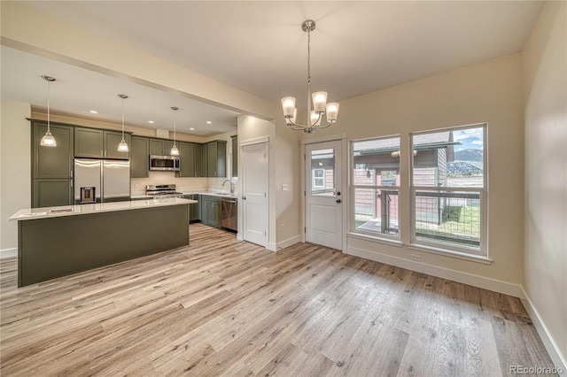 kitchen with a notable chandelier, a kitchen island, stainless steel appliances, and hanging light fixtures