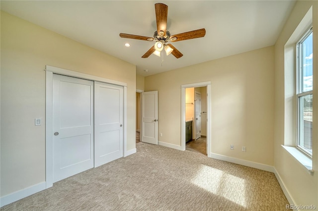 unfurnished bedroom with connected bathroom, ceiling fan, a closet, and light carpet