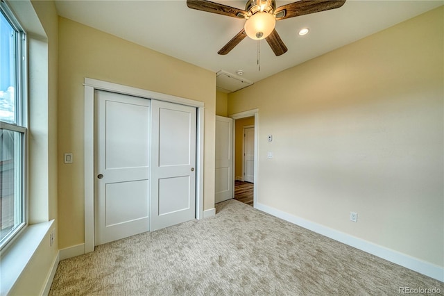 unfurnished bedroom featuring multiple windows, light carpet, a closet, and ceiling fan