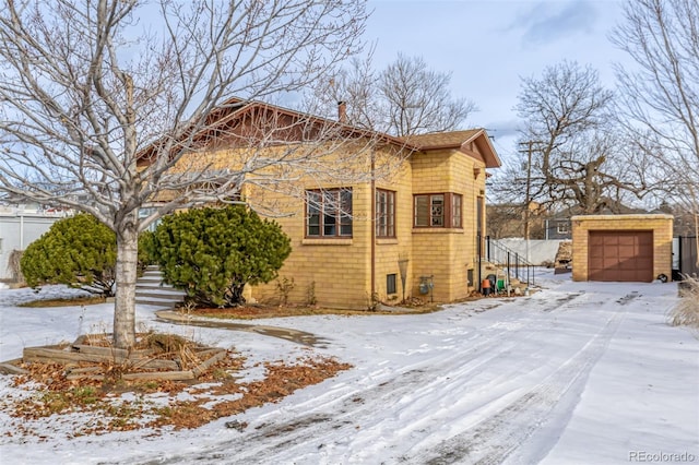 view of snow covered exterior with a garage and an outdoor structure